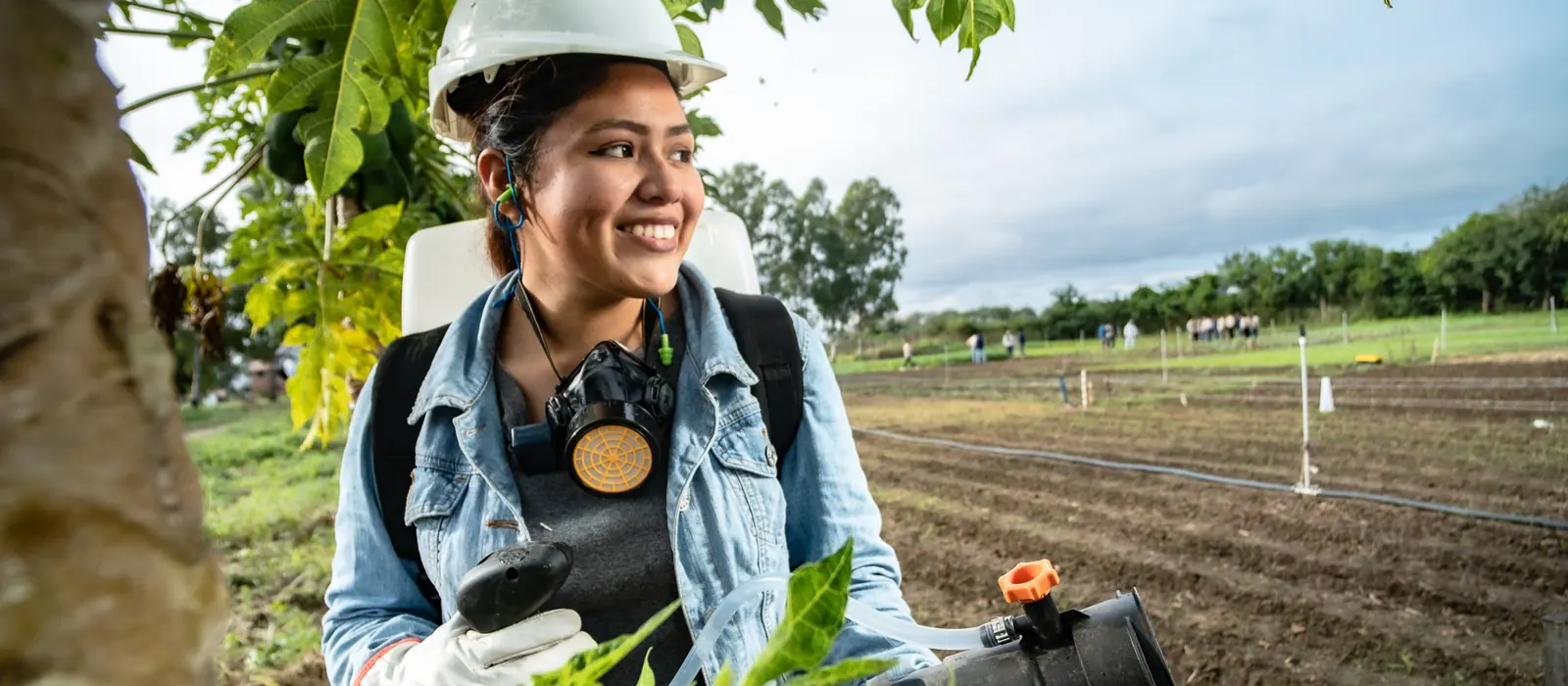 Joven t&eacute;cnica en agronom&iacute;a con equipo de protecci&oacute;n en una parcela